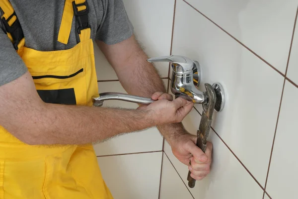 配管工は バスルームやキッチンで蛇口を固定または交換し 手を閉じて タップし 調整可能なレンチツール — ストック写真