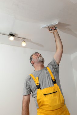Worker repairing plaster at ceiling clipart