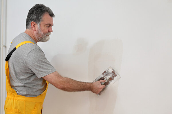 Worker repairing plaster at wall