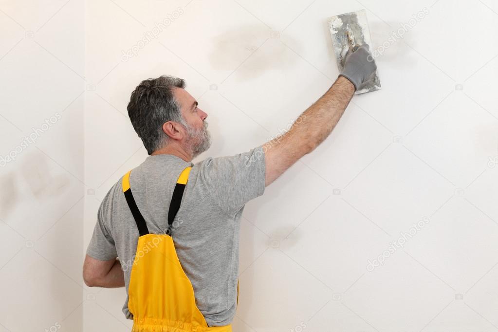 Worker repairing plaster at wall