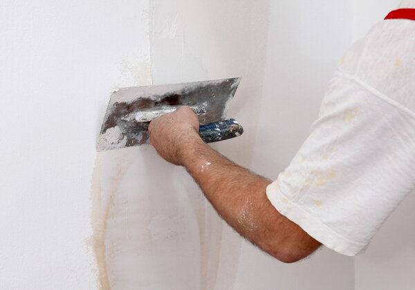 Worker repairing plaster to wall