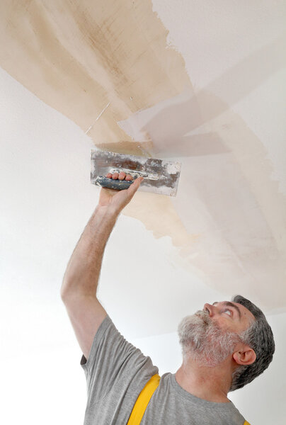 Worker repairing plaster at ceiling