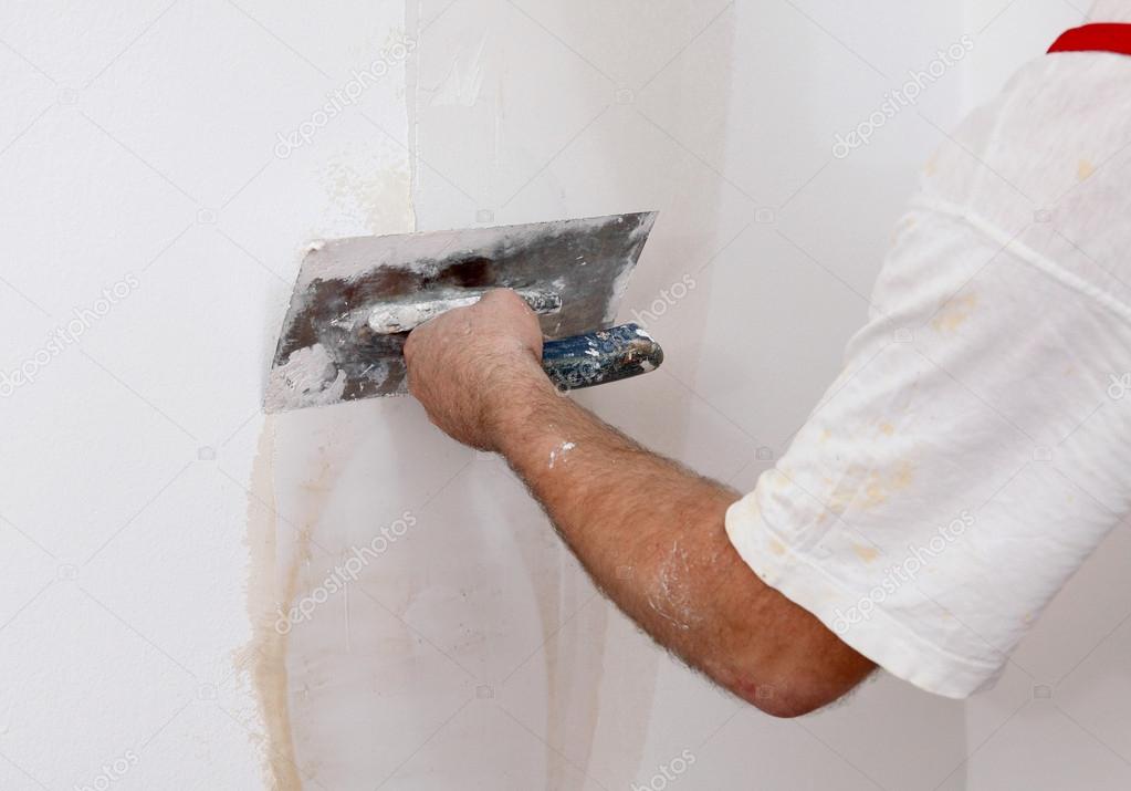 Worker repairing plaster to wall