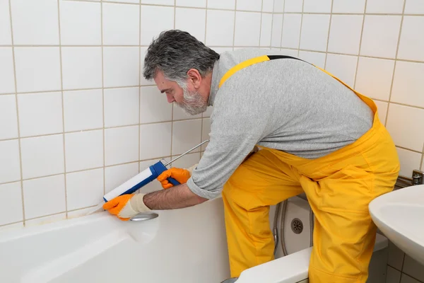 Trabajador calafateo tubo de baño y azulejos —  Fotos de Stock