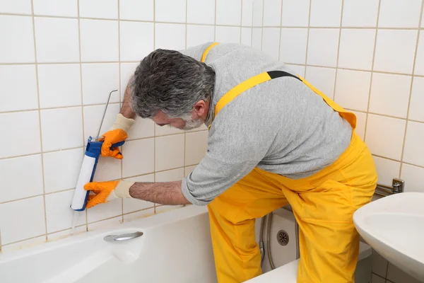 Worker caulking bath tube and tiles — Stock Photo, Image