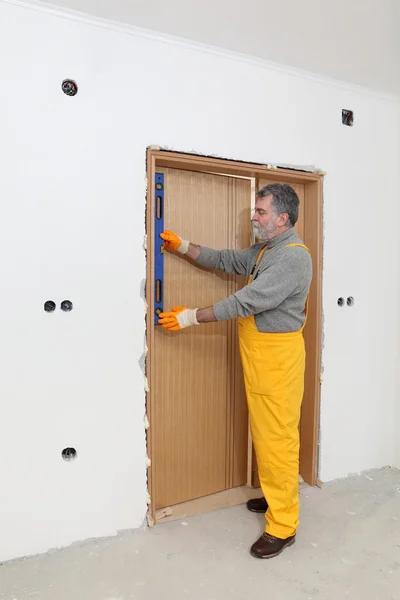 Bauarbeiter messen Vertikalität der Tür mit Niveauwerkzeug — Stockfoto