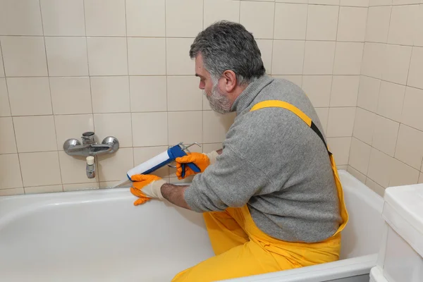 Trabajador calafateo tubo de baño y azulejos —  Fotos de Stock