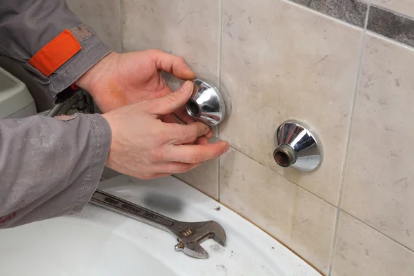Plumber fixing faucet in a bathroom Stock Picture