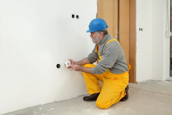 Elektricien bij bouw site installeren elektrische stekker Rechtenvrije Stockfoto's