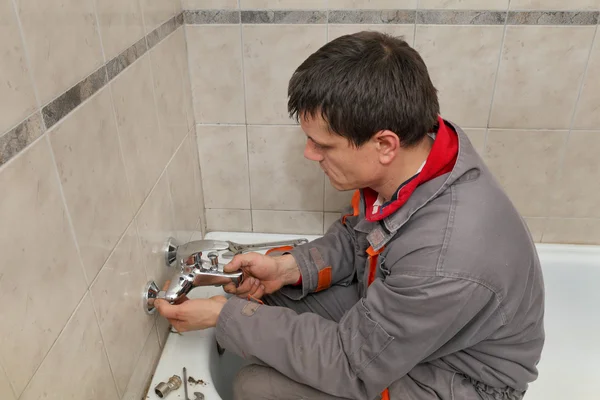 Plumber works in a bathroom — Stock Photo, Image