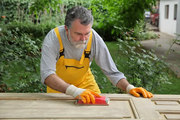 Renovierung des Hauses, Arbeiter schleifen Holztür — Stockfoto