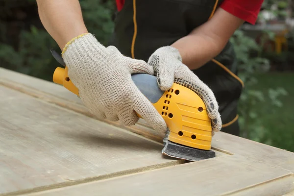 Home renovation, worker sanding wooden door — Stock Photo, Image