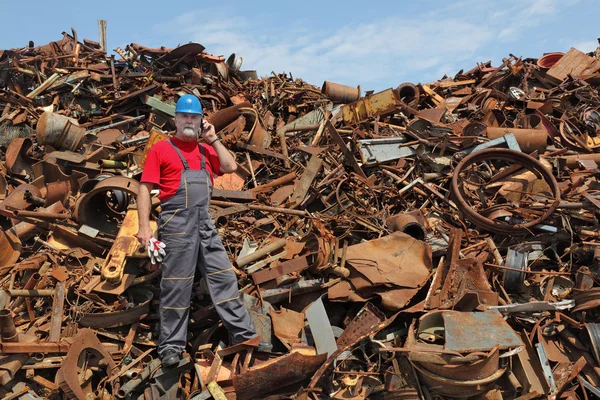 Recycling-Industrie, Arbeiter benutzen Telefon auf einem Haufen von altem Metall — Stockfoto