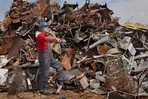 Indústria de reciclagem, trabalhador usando telefone em pilha de metal velho — Fotografia de Stock