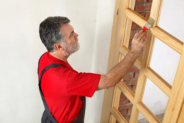 Home renovation, worker painting wooden door, varnishing — Stock Photo, Image
