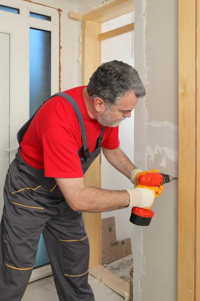 Construction site, worker installing gypsum board using electric tool — Stock Photo, Image