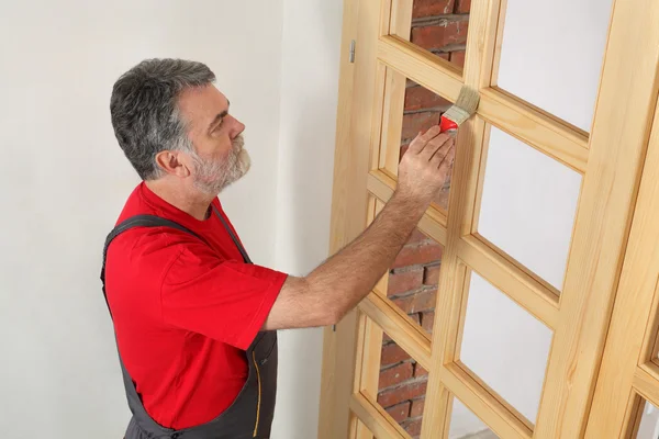 Home renovation, worker painting wooden door, varnishing — Stock Photo, Image