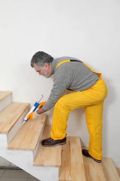 Renovación del hogar, calafateo de escaleras de madera con silicona — Foto de Stock