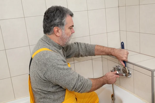 Loodgieter werkt in een badkamer bad toob kraan vaststelling — Stockfoto