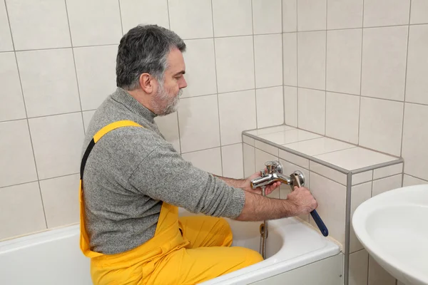 Loodgieter werkt in een badkamer bad toob kraan vaststelling — Stockfoto