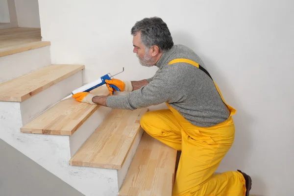 Casa renovação, calafetagem escadas de madeira com silicone — Fotografia de Stock