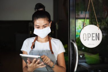 Mutlu Taylandlı garson, koruyucu maskeli, elinde tablet, restoranın yeniden açılması, Tayland, Koh Phangan 