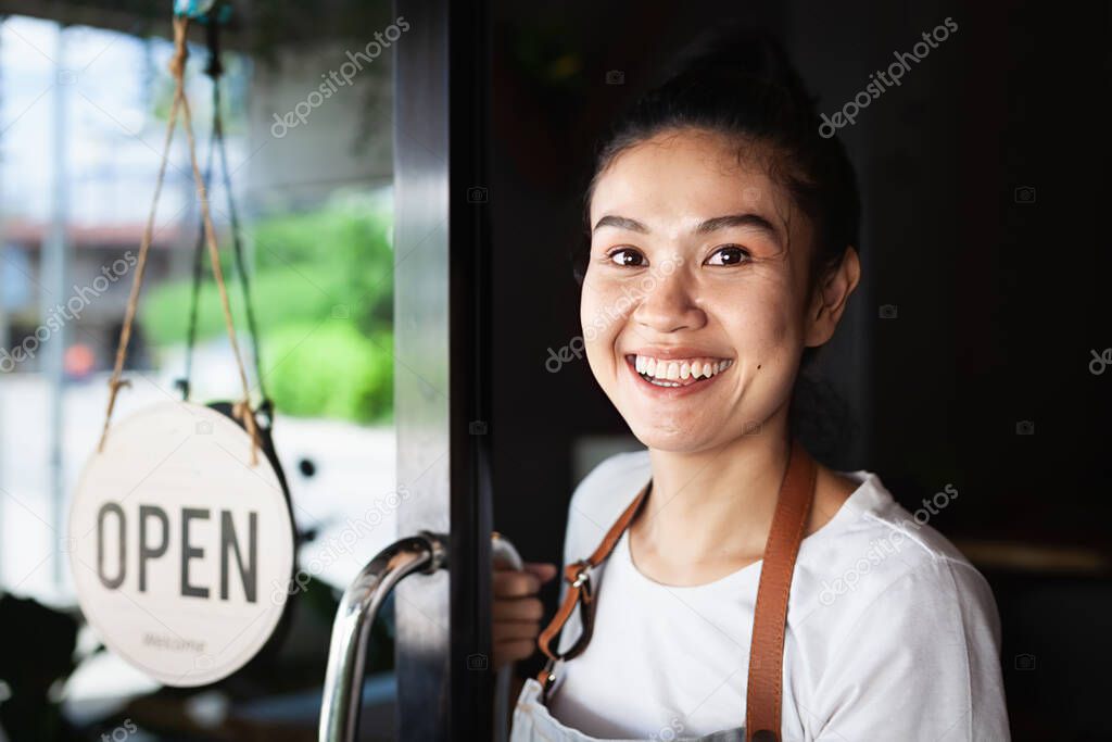 Young smiling Thai waitress, standing at doorway,  restaurant reopening, Thailand, Koh Phangan 