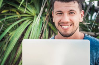 Plaj yaşam tarzında dizüstü bilgisayarı olan serbest çalışan bir adam.
