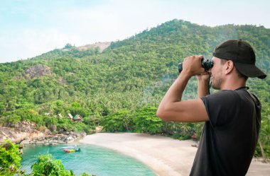 Dürbünlü bir adam etrafındaki güzel doğayı inceler, Koh Phangan, Tayland