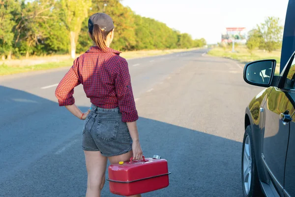 車の近くにガソリンのキャニスターと美しい若い女性 シャツとジーンズの少女は彼女の車を修理する準備ができている 女性整備士 — ストック写真