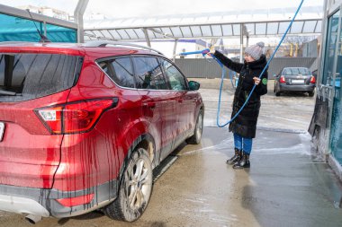 Otomatik yıkamada araba yıkama. Araba yıkama, su basıncının altında kırmızı makine araba yıkama, köpük içinde araba yıkama. Kadın araba yıkıyor.
