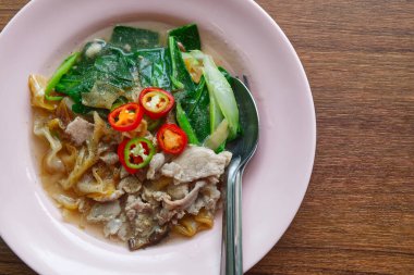 Ahşap masanın üstünde domuz soslu kızarmış pirinç eriştesi..