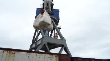 Yaz, 2020 - Vladivostok, Rusya - Deniz Konteynırı Terminali. Büyük bir liman vinci değerli çantaları demiryolu vagonlarına ve limandaki bir ticaret gemisine yükler.