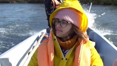 Genç bir kız nehir boyunca Udege teknesine biner ve etrafa bakar. Bir turist nehirde bir tekneye biniyor.