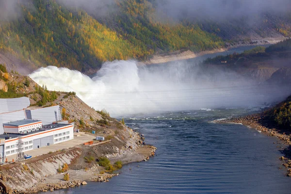 Kolyma vodní elektrárna v regionu Magadan, Rusko. Spillway z přehrady vodní elektrárny. Obrovský proud vody teče do řeky na pozadí vysokých kopců — Stock fotografie