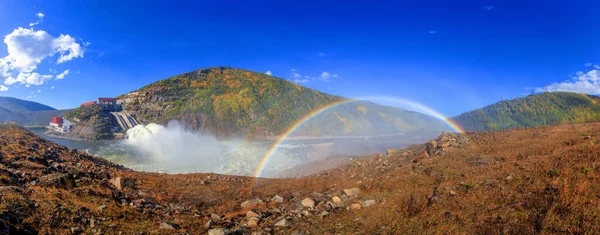 Un bel arc-en-ciel lumineux en pleine grandeur sur fond de collines d'automne et d'un petit ruisseau. Arc-en-ciel sur l'hydroélectricité pendant le déversement — Photo