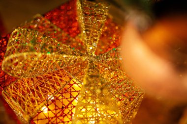 Yeni yıl teması. Yakın plan. Yılbaşı hediyesi dekoratif kutusu, odağından fırlamış, parlak renklerle parıldıyor. Kutudaki altın fiyonk.