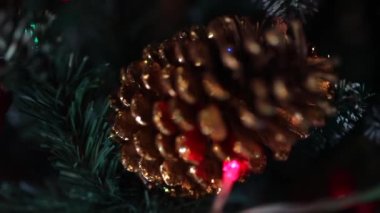 Noel canlı yayında. Yeni yıl oyuncağı. Macro vuruldu. Bir Noel ağacı oyuncağı. Kahverengi bir koni şeklinde. Yeni yıl ağacının kenarlarında parıldıyor..