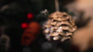 Noel canlı yayında. Macro vuruldu. Odaklanamıyorum. Yeni yıl ağacında parıldayan kahverengi koni şeklinde bir Noel ağacı oyuncağı.