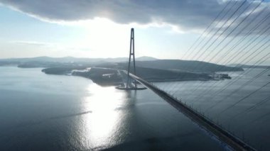 Rus köprüsünün üst görüntüsü. Arka planda Russky Adası var. - Rusya. Kamera kışın gün batımında Rus Köprüsü yakınlarında uçar..