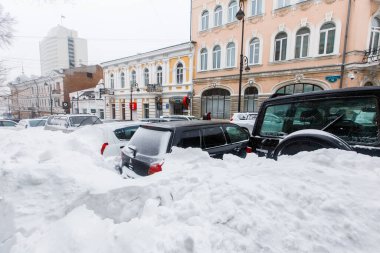 Ocak 2016 - Vladivostok, Rusya - Vladivostok 'ta yoğun kar yağışı. Yoğun kar altında yol kenarında karla kaplı arabalar duruyor.