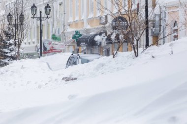 Ocak 2016 - Vladivostok, Rusya - Vladivostok 'ta yoğun kar yağışı. Yoğun kar altında yol kenarında karla kaplı arabalar duruyor.