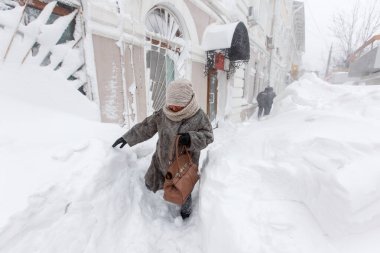Ocak 2016 - Vladivostok, Rusya - Vladivostok 'ta yoğun kar yağışı. İnsanlar Vladivostok 'un ana caddelerinde karla kaplı şekilde yürüyorlar. Yayalar şehirde büyük kar yığınlarının yanından geçiyor.