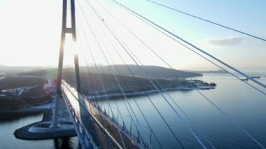 Yukarıdan bak. Doğu Boğazı 'ndaki Rus köprüsü Vladivostok' ta. Kamera, buz fırtınasının engellediği köprünün üzerinde yükseliyor. Droga giydiği için tıkandı. Günbatımı, akşam.