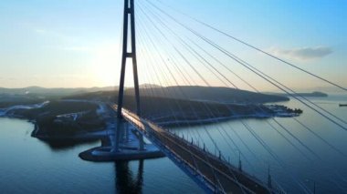 Yukarıdan bak. Doğu Boğazı 'ndaki Rus köprüsü Vladivostok' ta. Kamera, gün batımında kabloların buzlanması nedeniyle arabalardan uzak ve boş olan Rus köprüsünün yanından uçuyor.