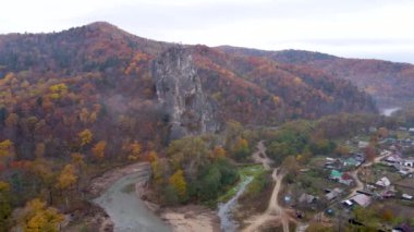 Yukarıdan bak. 4 bin. Kavalerovo köyündeki Dersu Uzala kayası, sahil bölgesi. Sonbahar mevsiminde bir Rus köyü ve parlak bir ormanın arka planına karşı resim gibi bir kaya..