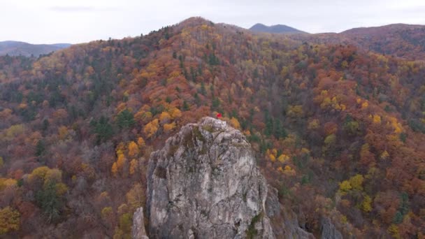 从上面看4K 普里莫尔斯基县Kavalerovo村的Dersu Uzala岩石 相机在秋天森林的背景下 从一个风景如画的悬崖顶上放大 悬崖顶上飘扬着红旗 — 图库视频影像