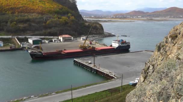2020 Rudnaya Pristan Russia 掘削機は小さな商船から石炭をアンロードします 商船は石炭を卸す時に停泊している — ストック動画