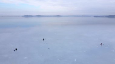 Vladivostok 'taki Amur Körfezi' nin buzunda kış balıkçılığı. Yukarıdan bak. Üç balıkçı uzak bir diyarın arka planında ince buzda balık tutuyor..