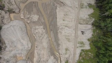 Yukarıdan bak. Altın madeninin orada kapana kısılmış bir nehir. Kamera çamurlu bir nehrin üzerinde uçuyor ve bir altın madeni inşaatındaki inşaat yolunda. Ekolojik felaket.